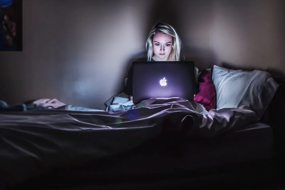 Woman sitting on bed looking at laptop